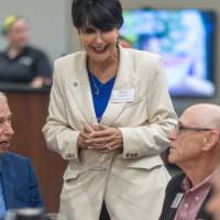 President Mantella standing while talking with event attendees at table
